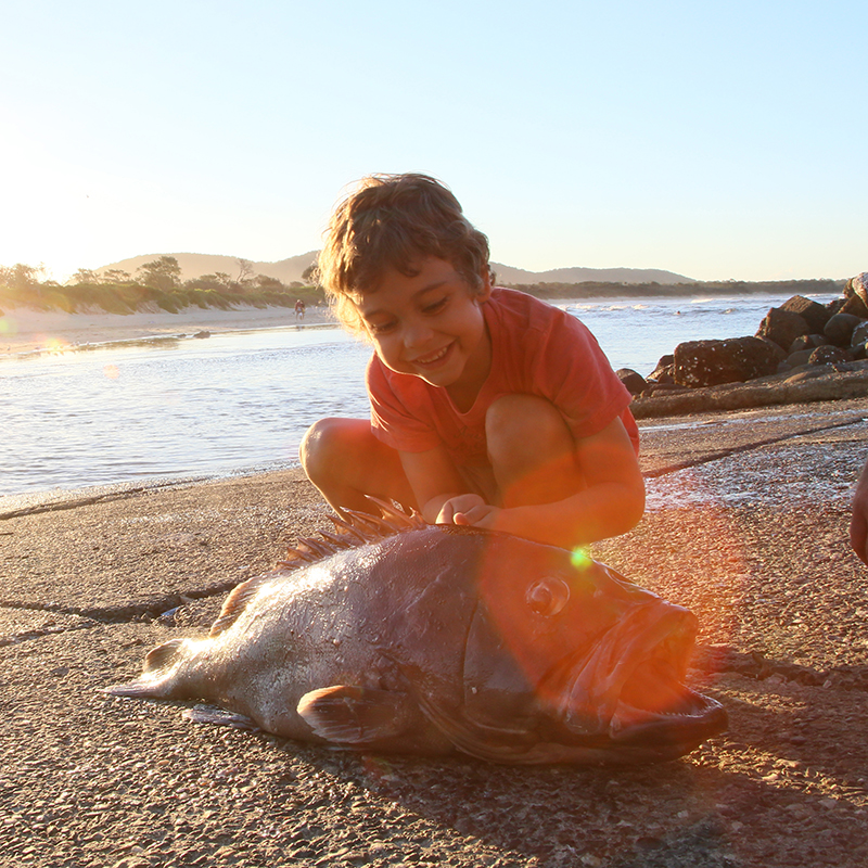young boy at Crescent Head beach after catching a large fish