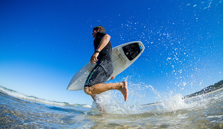 man going for a surf at hat head beach