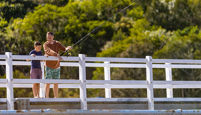 Father and son fishing off bridge