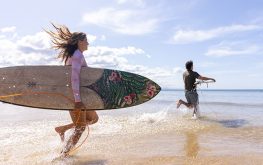 Couple running into water with surfboards